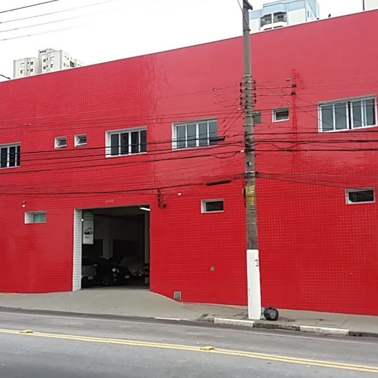 Fachada vermelha da Vitorauto, com o portão aberto para a oficina